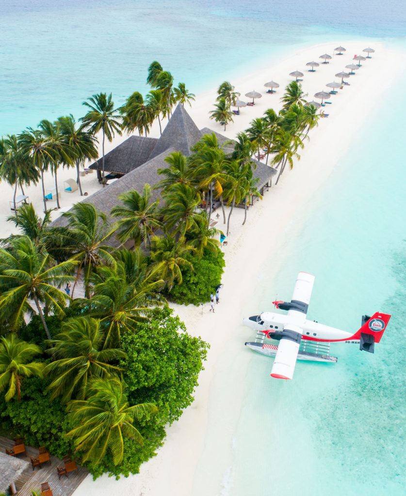 a plane flying over a tropical beach