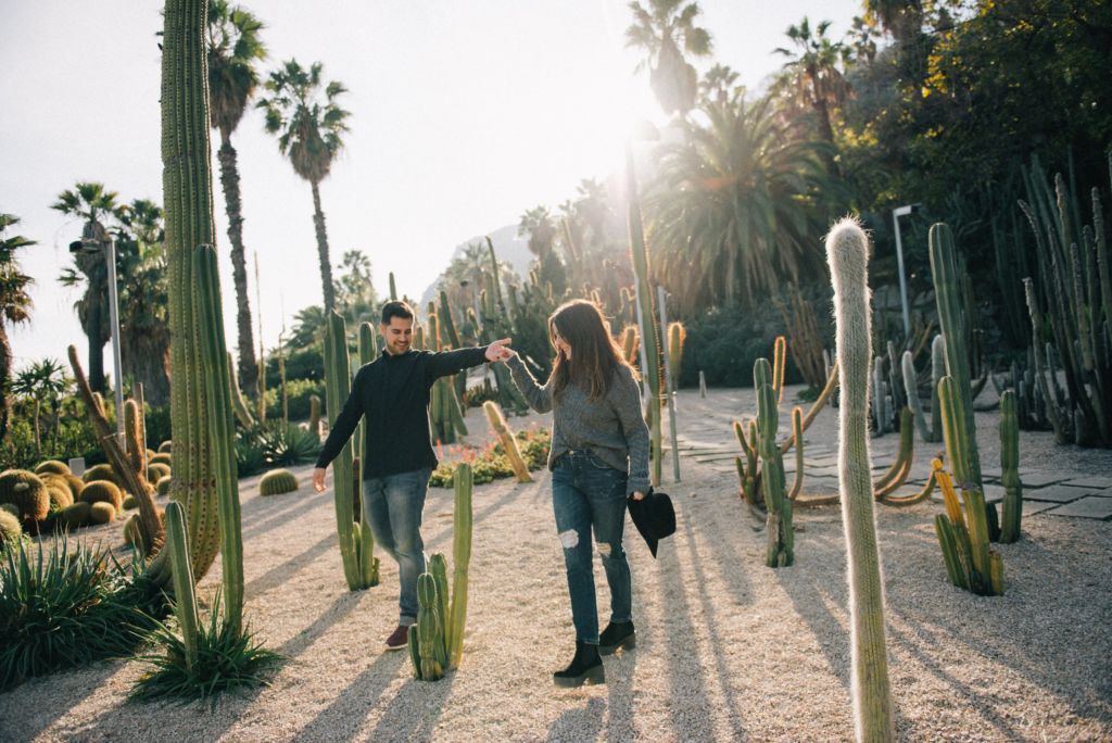 a man and woman walking on a path in a tropical area