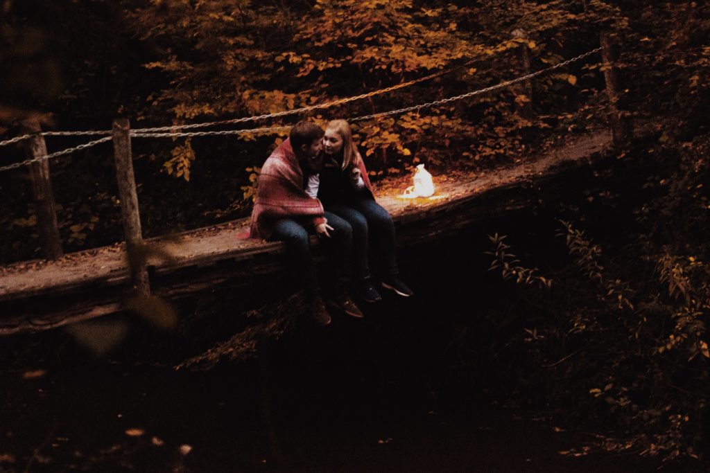 a man and woman sitting on a bench by a fire