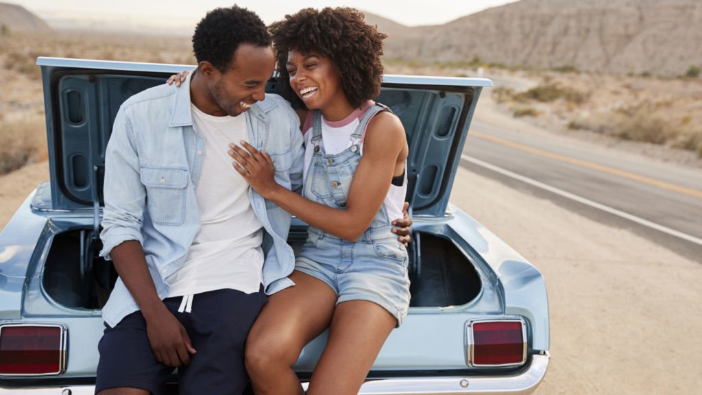 a man and woman sitting in a car with their hands on the door